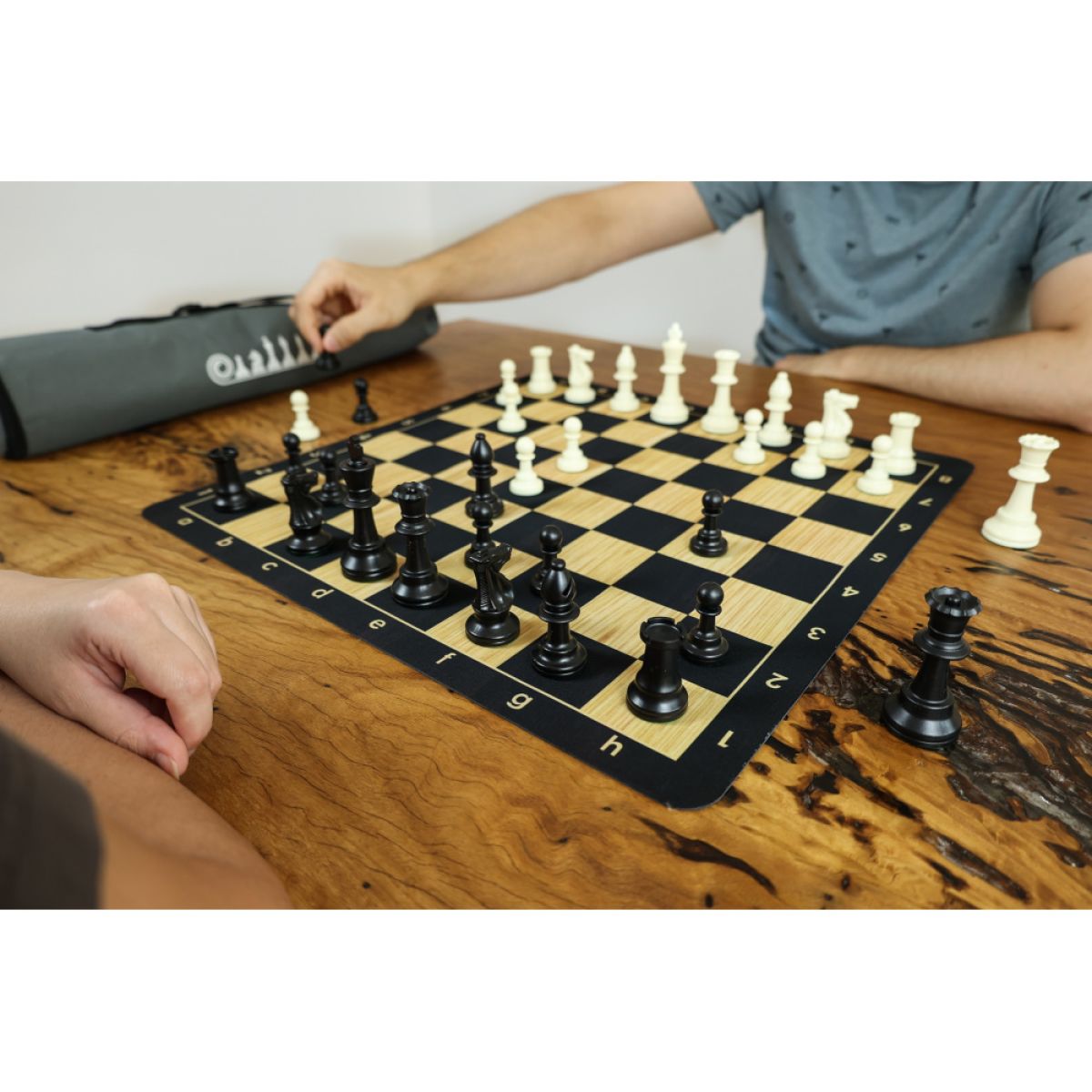 a man playing a game of chess on a wooden table